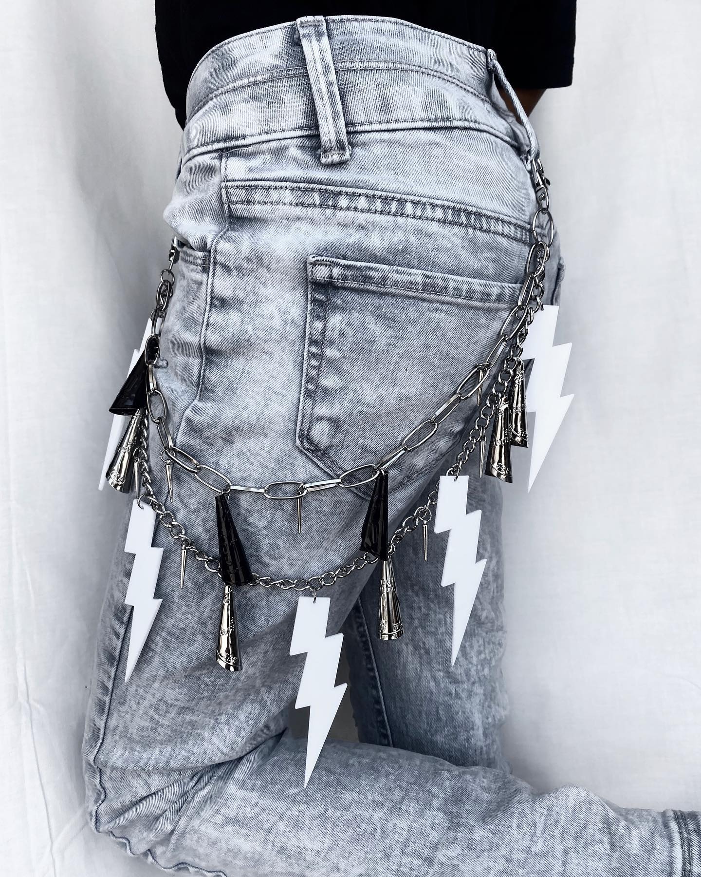 Black jingles, silver jingles, spikes, and five acrylic lightning bolt charms are on this Moth To The Flvme two layered jingle pant chain